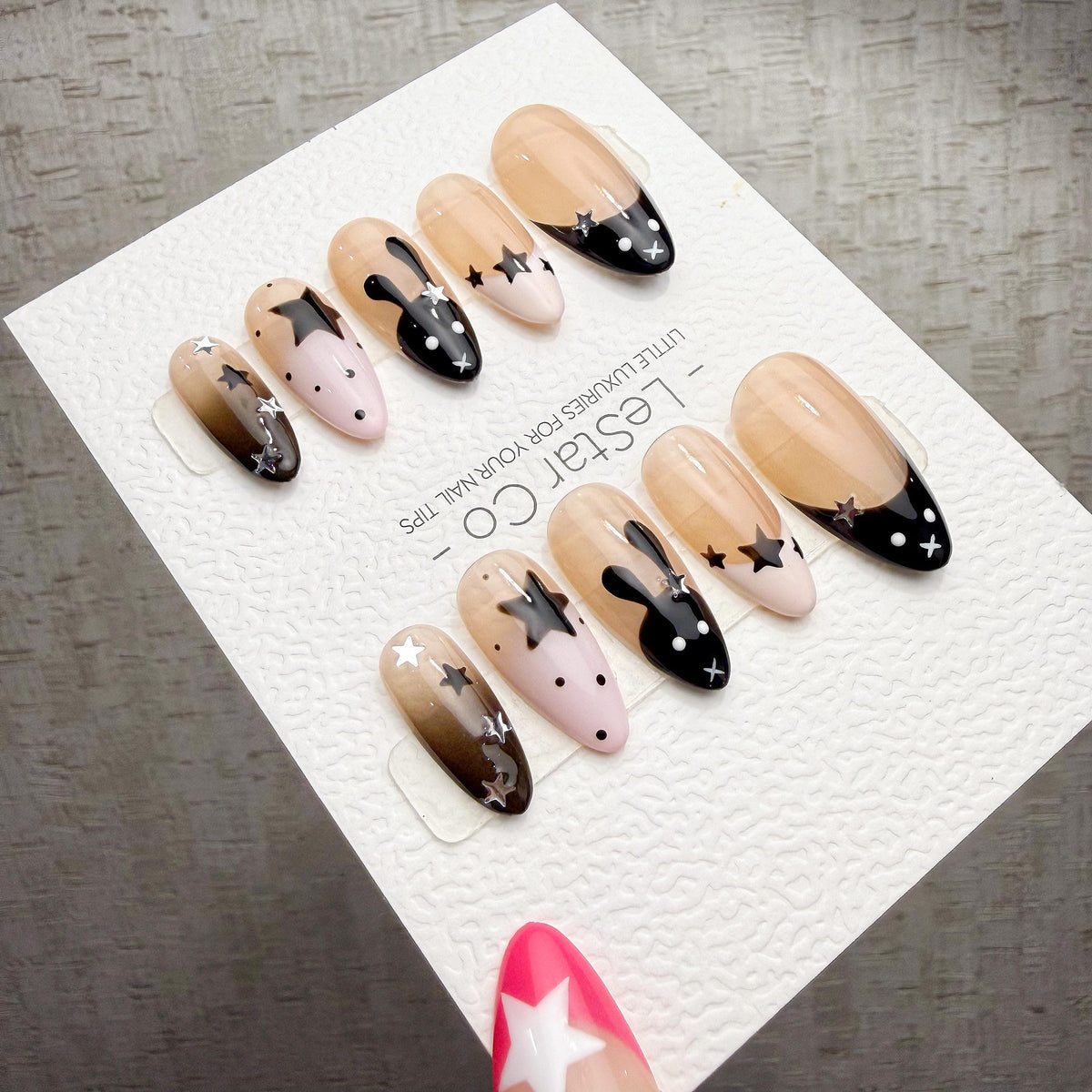 A collection of elaborately decorated nails with various star and bunny designs, displayed on a white background.