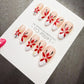 A set of elaborately decorated fingernails with red and white floral designs.