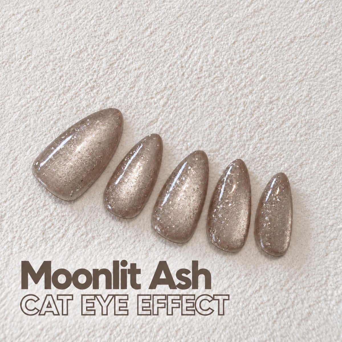 a collection of glittery nail polish bottles arranged on a white surface, with the text "Moonlit Ash CAT Eye Effect" written below them.