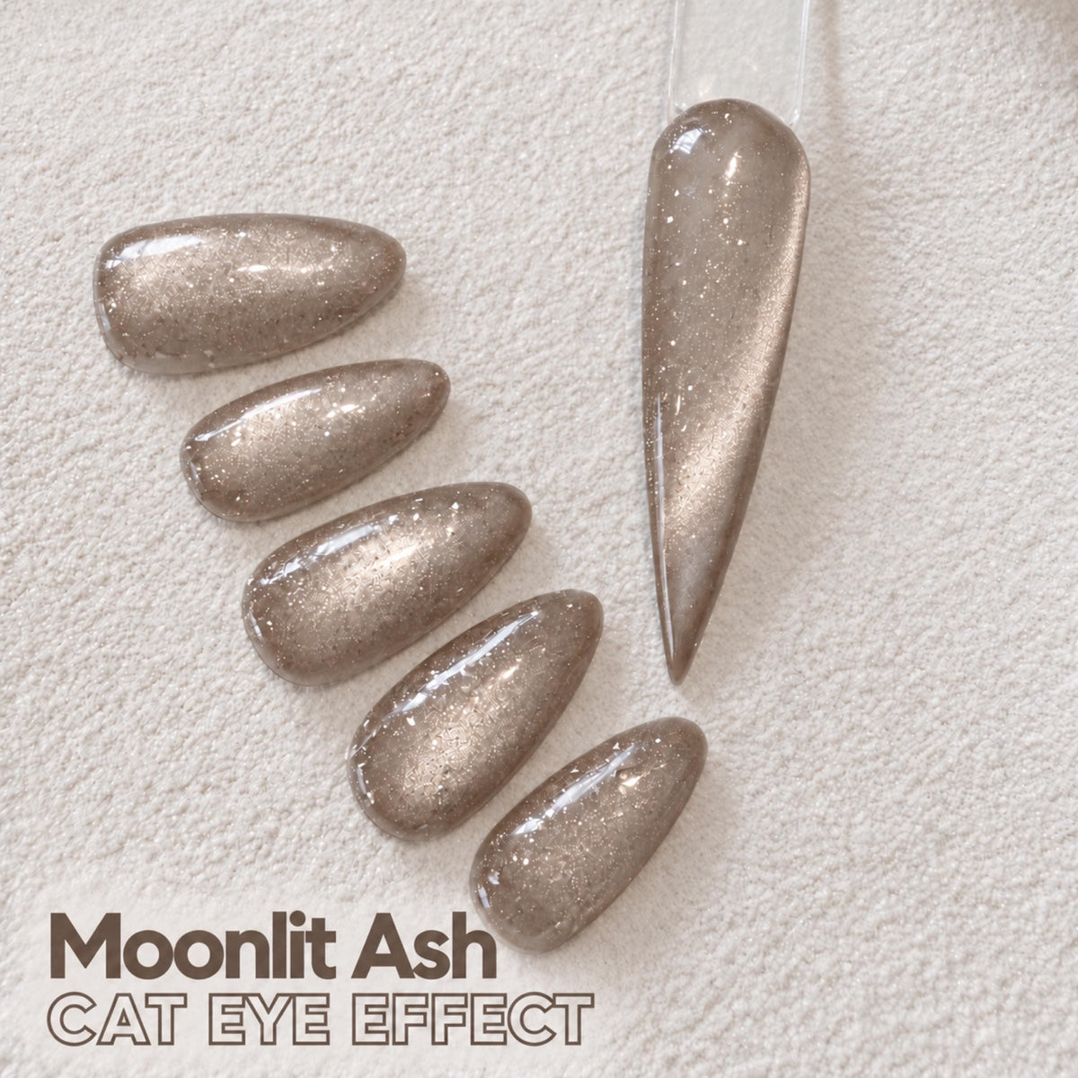a collection of glittery nail polish bottles arranged on a white surface, with a nail polish bottle labeled "Moonlit Ash CAT Eye Effect" in the foreground.