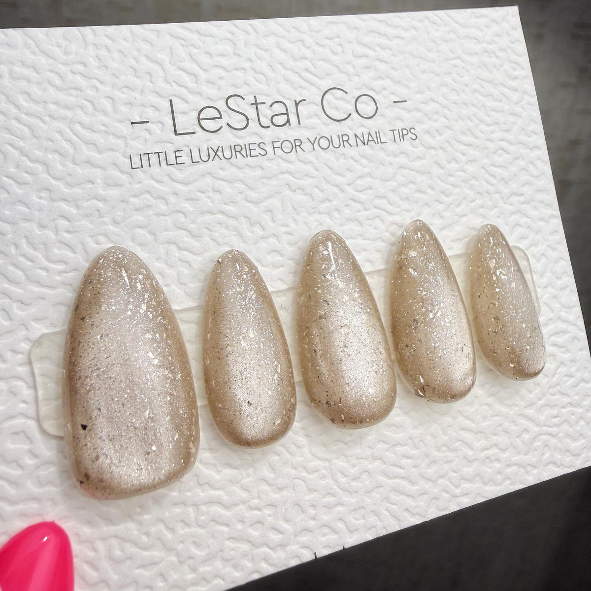 A set of gold glittery nail art designs on a white background, with the text "LeStar Co - LITTLE LUXURIES FOR YOUR NAIL TIPS" visible.