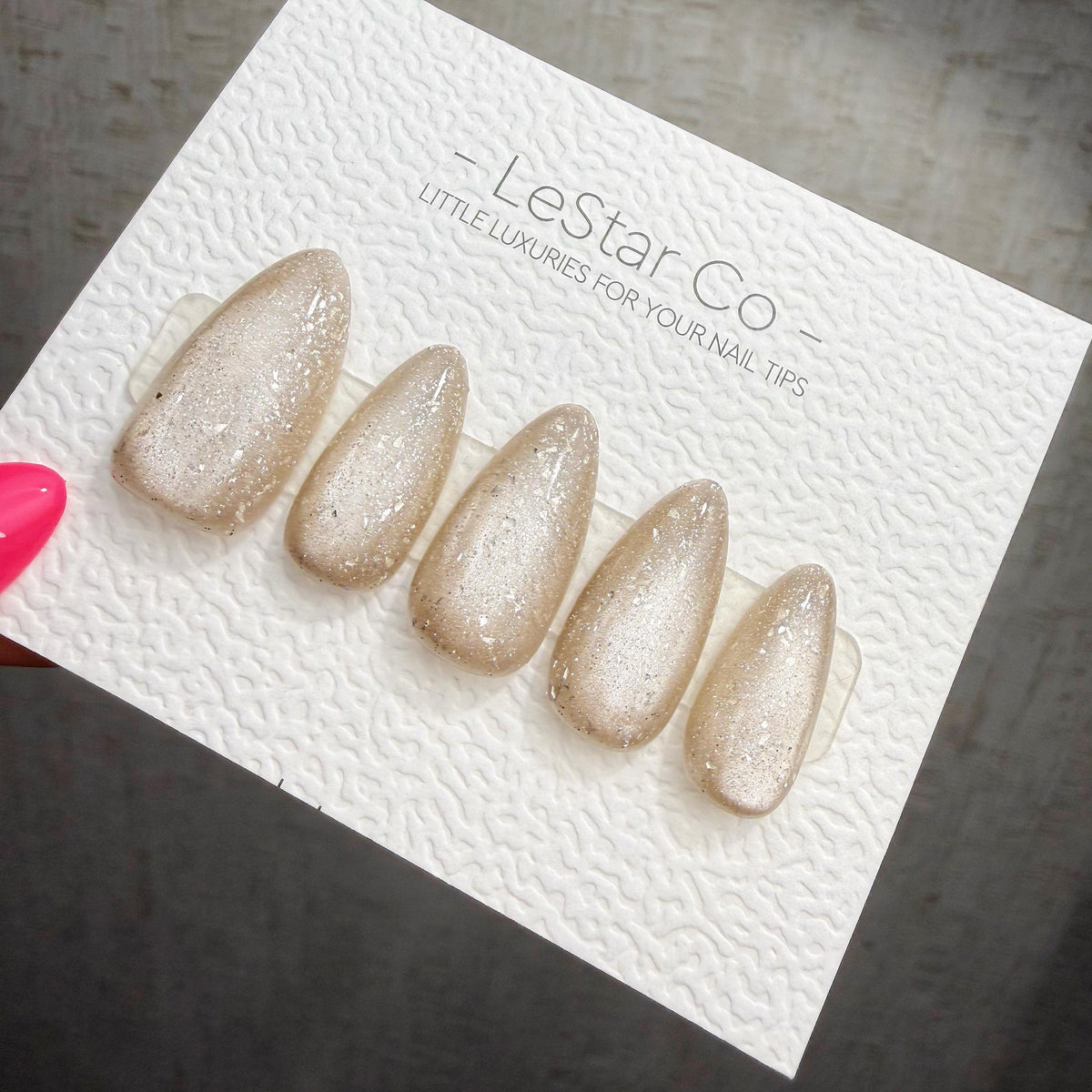 A close-up of a white card with a row of glittery nail polish bottles on it, along with the text "LESS THAN 500" and "LESS THAN 500" printed on it.