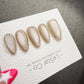 A close-up of a white card with text and images of glittery nail art designs.